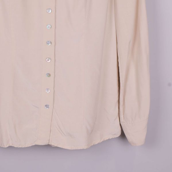 Detalj av ärmslut och nedre del på beige blus