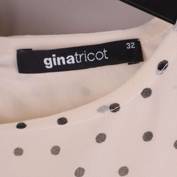 Närbild på Gina Tricot-etikett och storlek 32 i halsen på klänningen