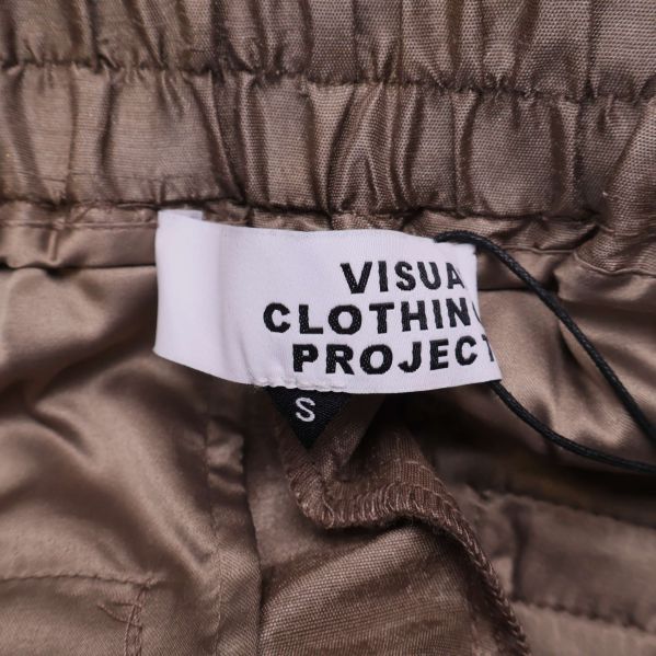 Närbild på varumärkestagg Visual Clothing Project och storlek S