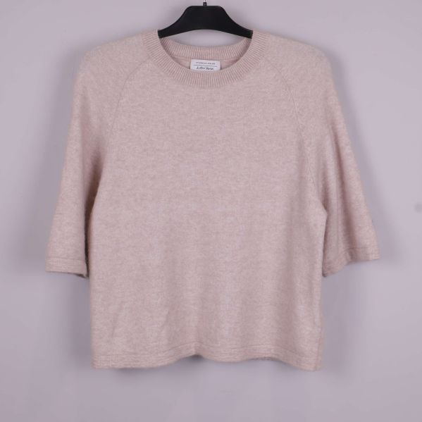 Stickad tröja i beige på galge framifrån