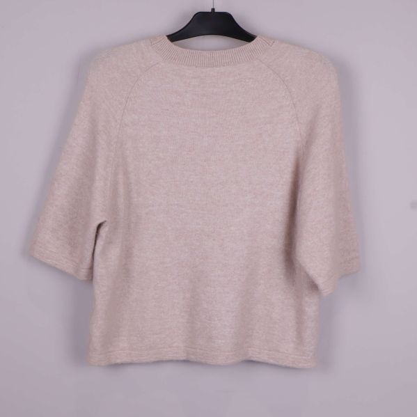 Stickad tröja i beige på galge bakifrån