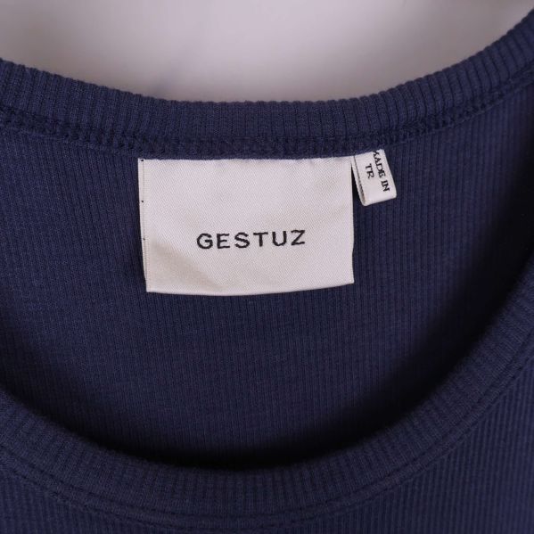 Närbild på klänningsetikett med Gestuz-logga