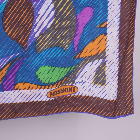 Närbild på scarfrand med Missoni-logotyp och färgade linjer