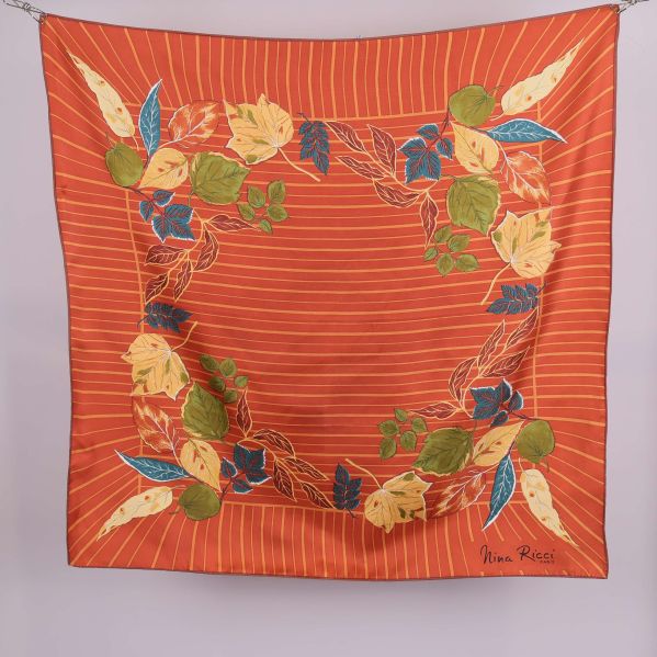 Kvadratisk scarf med orange botten och bladmotiv i olika färger