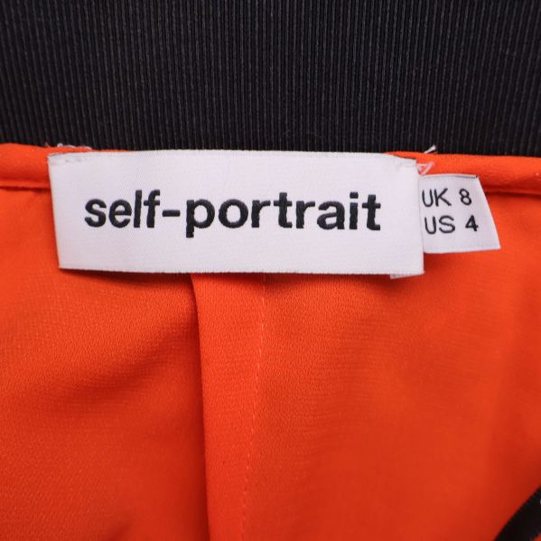 Närbild på Self-Portrait varumärkestagg i kjolen
