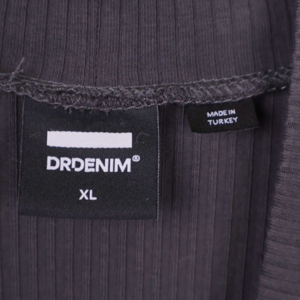 Närbild på Dr Denim logotyp och storlekslapp XL