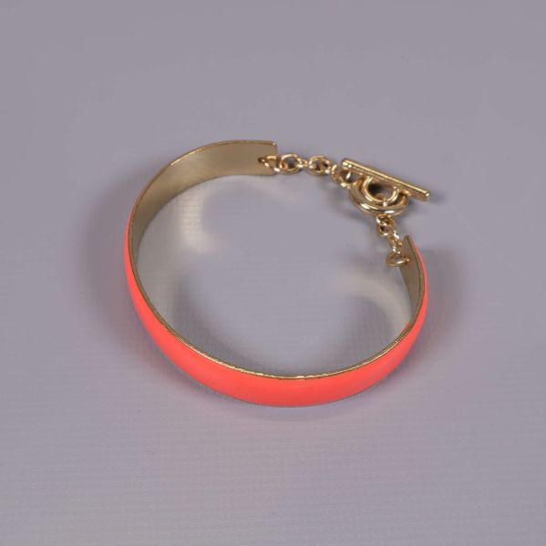 Korallfärgat armband med gulddetaljer i närbild