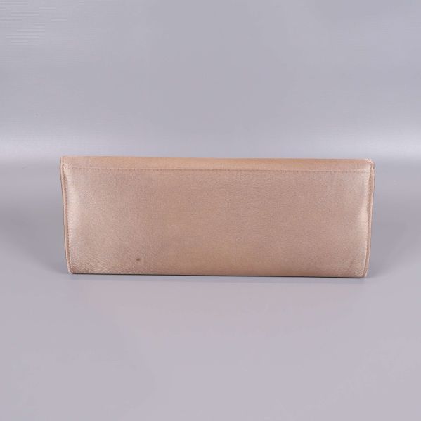 Baksida av clutch i ljusguld med liten fläck