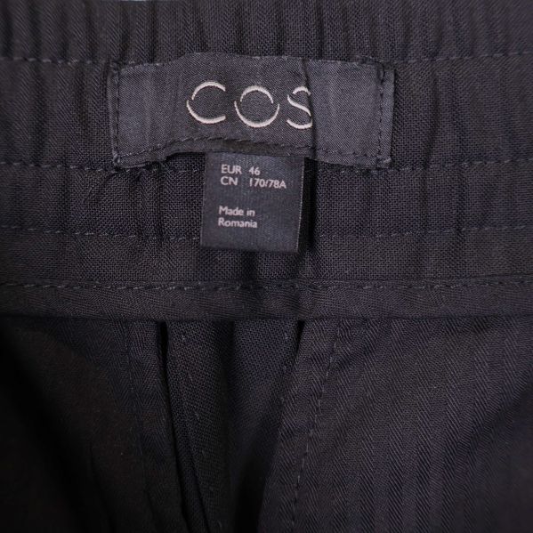 COS-label och storlekstagg i midjan på byxa