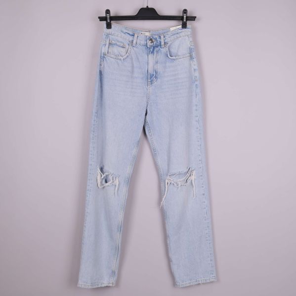 Framsida av ljusblå jeans med slitningar på knäna