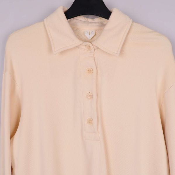 Knappslå och krage upptill på beige pikéklänning
