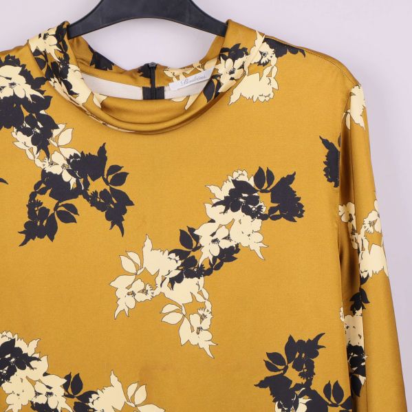 Närbild av halsringning och blommönster på topp