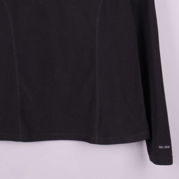 Detalj av svart fleece med TNF 100 text vid ärmslut
