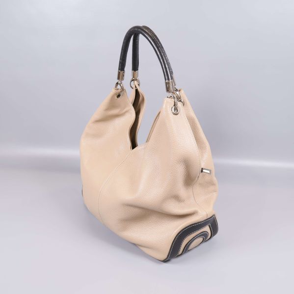 Snedvy på beige väska med mörkt handtag och dekorativ botten