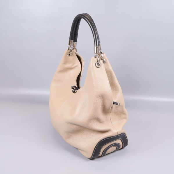 Beige axelväska med mörkt handtag och mönstrad botten