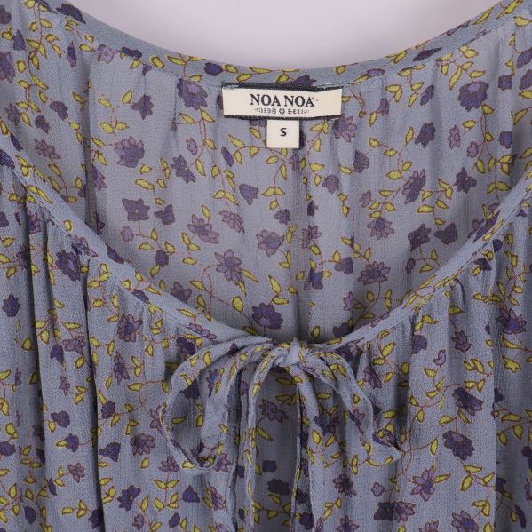 Närbild på blommig blus med etikett och snörning