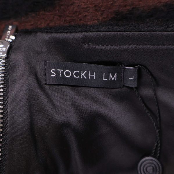 Närbild på svart etikett med texten STOCKH LM i kjol