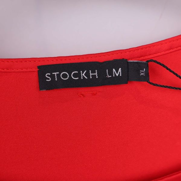 Närbild på etikett vid halsen visar märket STOCKH LM