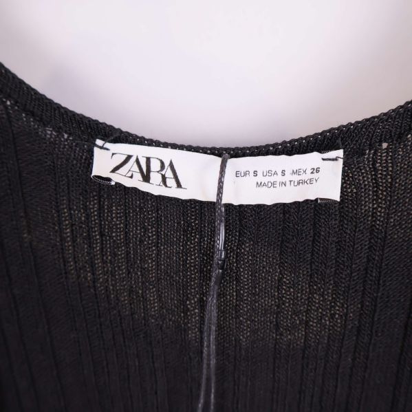 Närbild på vit Zara-label i nacken på svart jumpsuit
