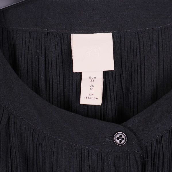 Närbild på krage och etikett med H&M logga i klänningen