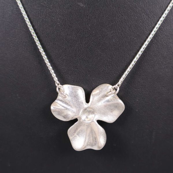Baksidan av blomformad berlock i matt silver
