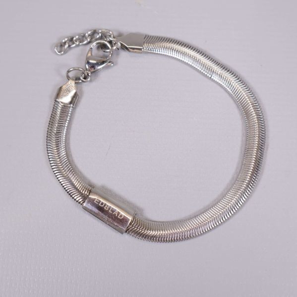 Närbild på armbandets glänsande ormkeja och märkeshänge
