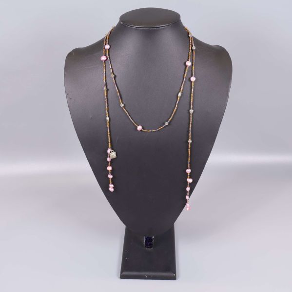 Långt halsband med bruna och rosa pärlor på svart ställ