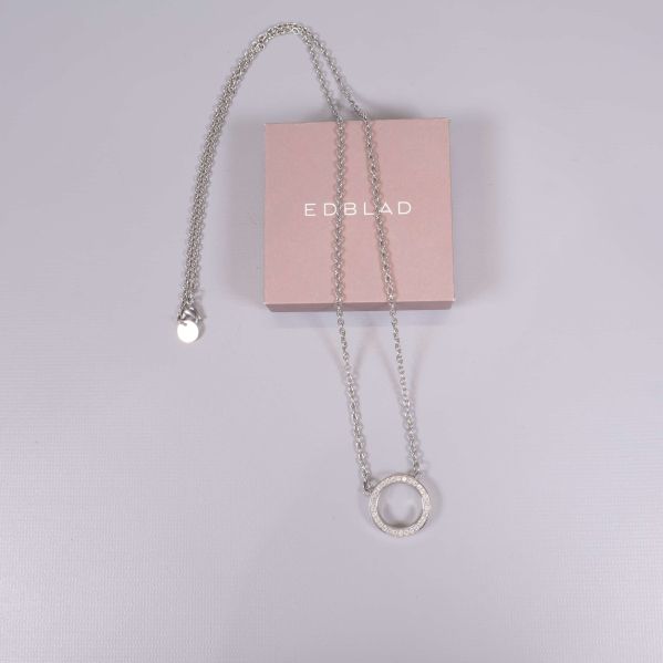 Halsband med cirkelformat hänge placerat på rosa ask