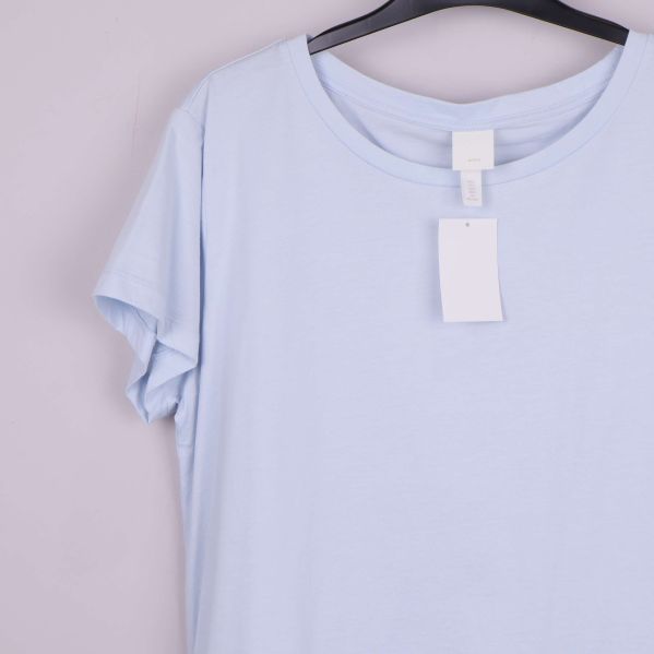 Ljusblå t-shirt med etikett i närbild framtill