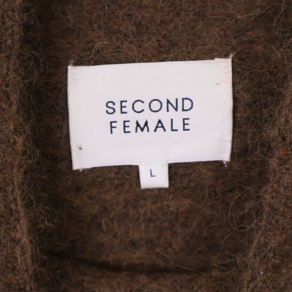 Närbild av vit etikett med Second Female logga i tröjans krage
