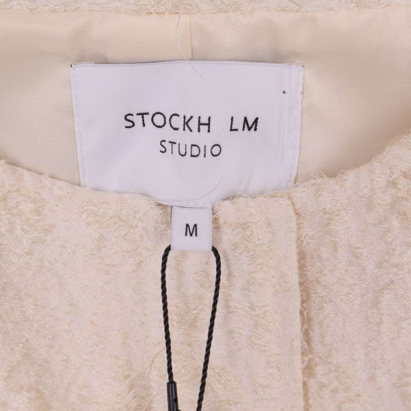 Närbild av inneretikett med varumärket STOCKH LM STUDIO och storlek M