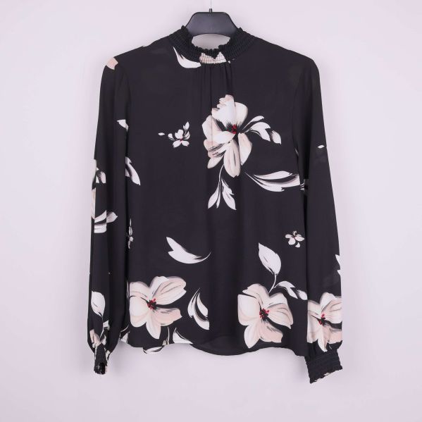Svart blus med stort blommönster på galge framifrån