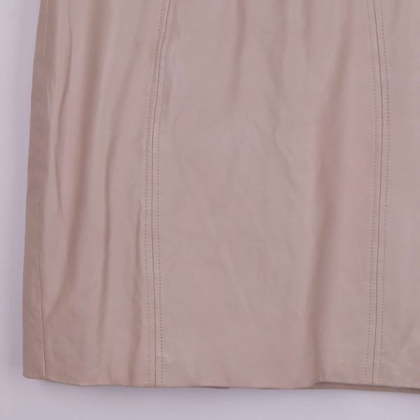 Närbild på nedre del av beige läderkjol