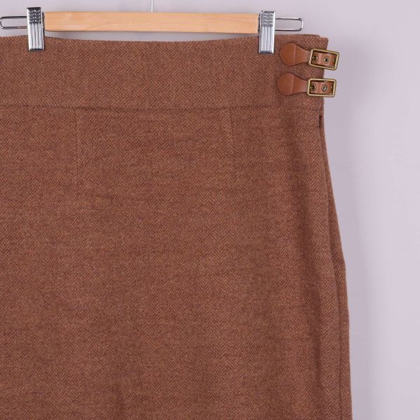 Övre del av brun kjol med fiskbensmönster och spännen