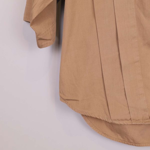 Närbild på fåll och sömmar nertill på beige blus