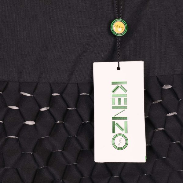 Närbild på Kenzo-tag fäst vid svart kjol med grafiskt mönster