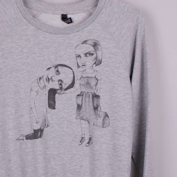 Närbild på grafiskt tryck med två karaktärer på grå sweatshirt