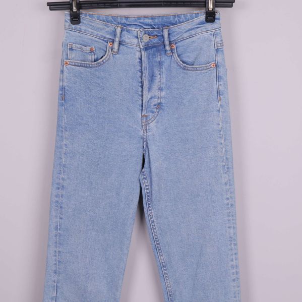Framsidan av ljusblå jeans med fickor och knapp