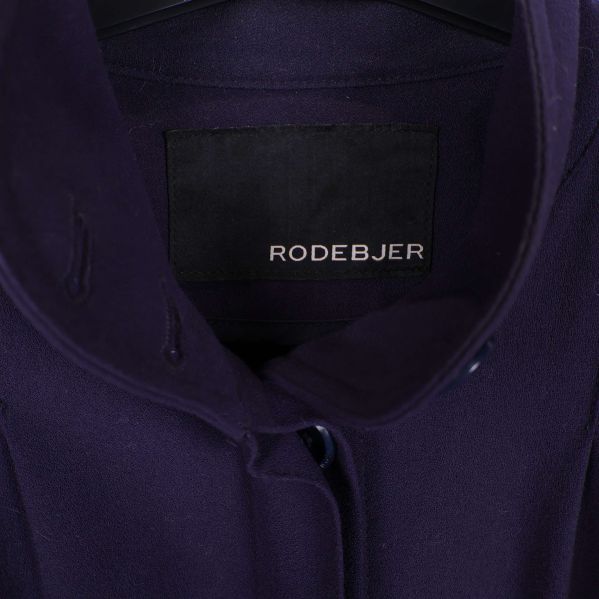 Närbild på Rodebjer logotyp i kappans krage