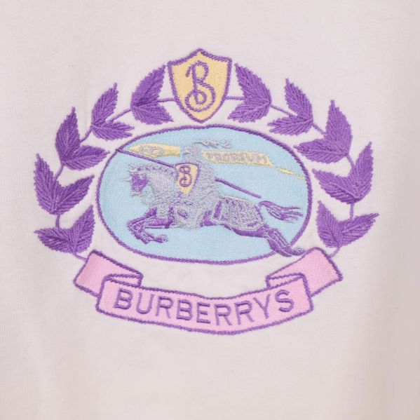 Närbild på broderad logotyp i lila och blått med Burberrys-text
