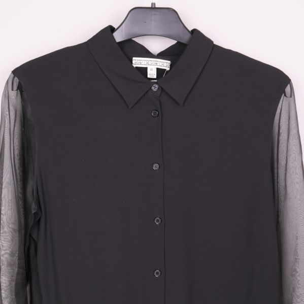 Närbild på krage och knäppning av svart blus med transparenta ärmar