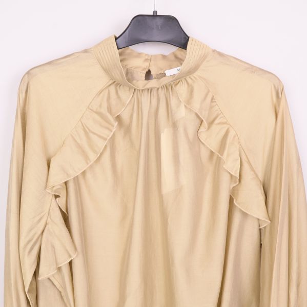 Närbild på volang och axelparti på beige blus