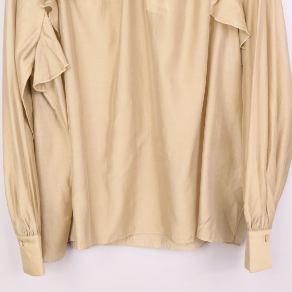 Nedre delen av beige blus med manschetter