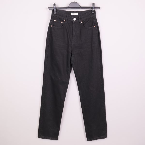 Svarta raka jeans upphängda på galge mot ljus bakgrund