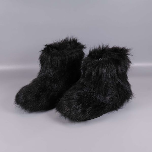 Ett par svarta boots med lång fuskpäls på grå bakgrund