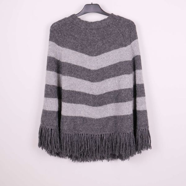 Baksida av grårandig stickad poncho med långa fransar