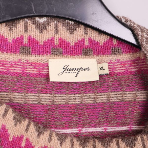 Närbild på etikett med varumärket Jumperfabriken och storlek XL