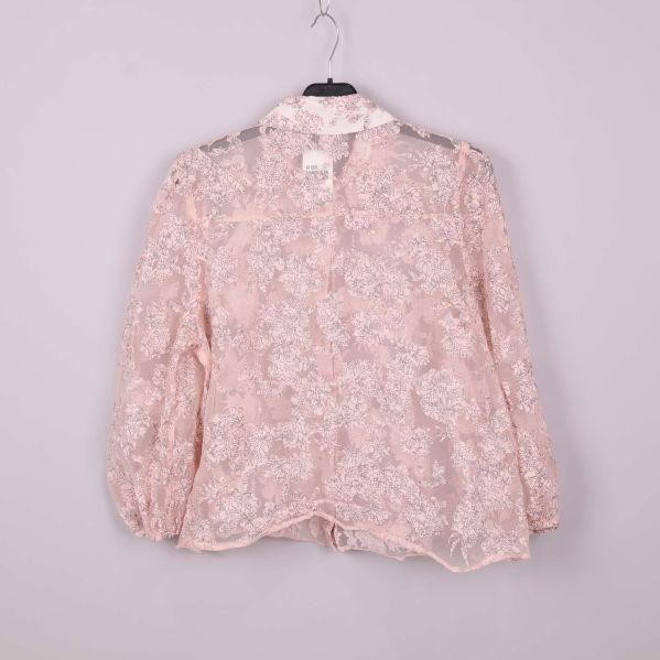 Transparant blus med blommönster bakifrån på galge