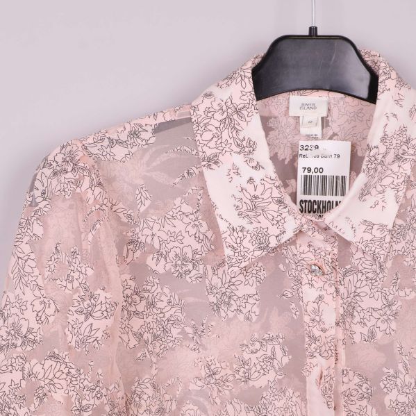 Närbild på halsringning och etikett på transparent blus
