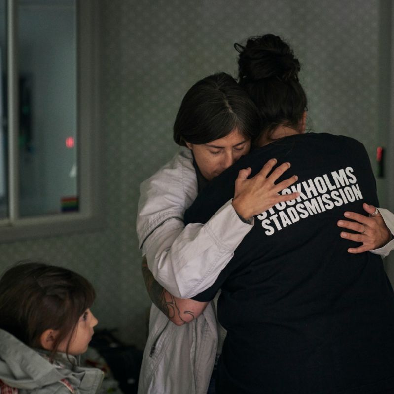 En mamma med barn kramas om av Stockholms Stadsmissions personal.